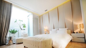 Una habitación de hotel moderna con una cama grande, una mesita de noche, una lámpara y una planta en maceta.