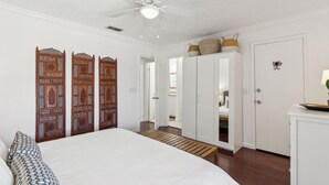 Camera da letto con un letto, una ventola a soffitto, un armadio e una porta con pannello decorativo.
