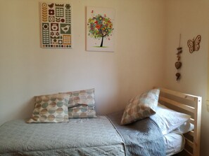 Un dormitorio con una cama, almohadas, una pared con adornos y una ventana.
