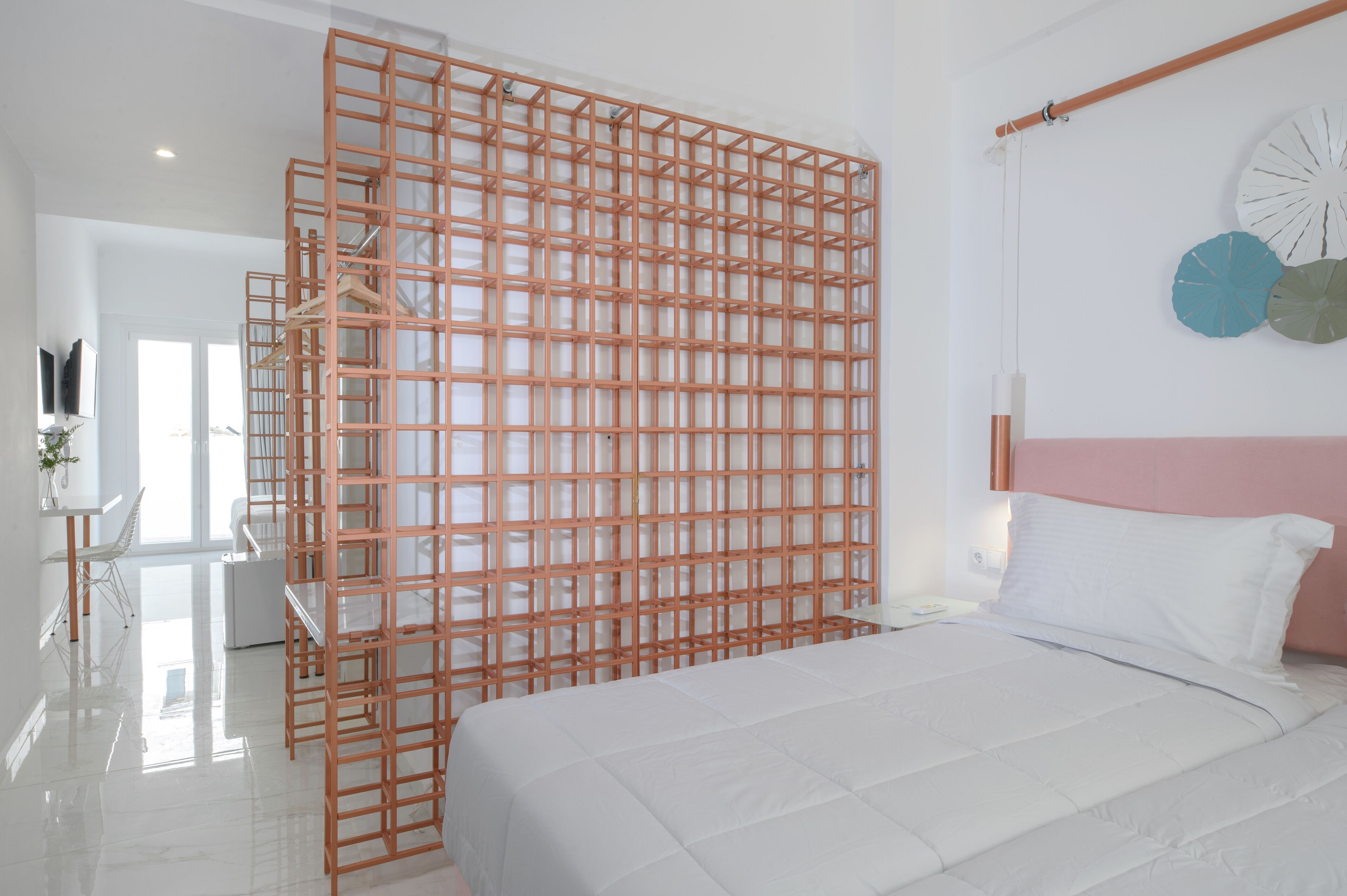 Un dormitorio con cama, cabecera blanca y separador de madera.