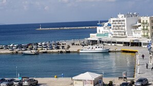 A coastal town with a marina, parked cars, and buildings with shops and restaurants. - Nama Boutique Hotel (Tinos)