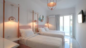 A hotel room with two beds, a large window, and a flat-screen TV mounted on the wall.