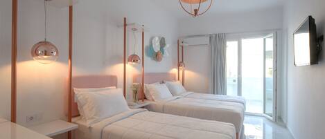 A hotel room with two beds, a large window, and a flat-screen TV mounted on the wall.