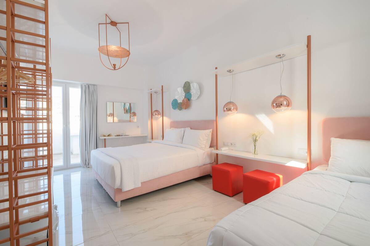 Ein modernes Hotelzimmer mit einem großen Bett, einem Schreibtisch und einem roten Hocker.