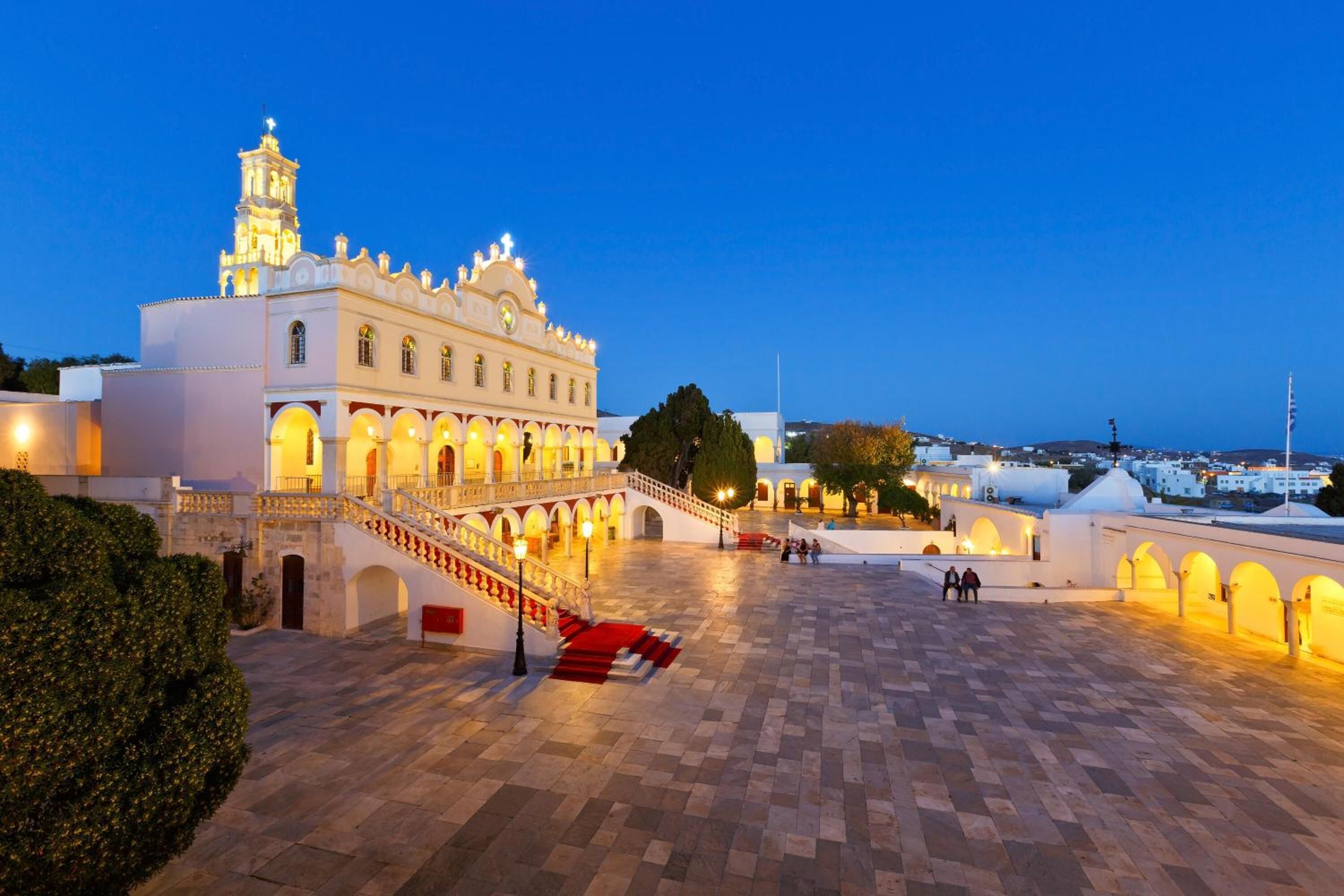 A historic building with a grand staircase leading to an upper level, surrounded by a spacious courtyard with a tiled floor.
