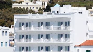 Een wit hotel met meerdere verdiepingen, balkons, een Eurobank bord en uitzicht op zee.