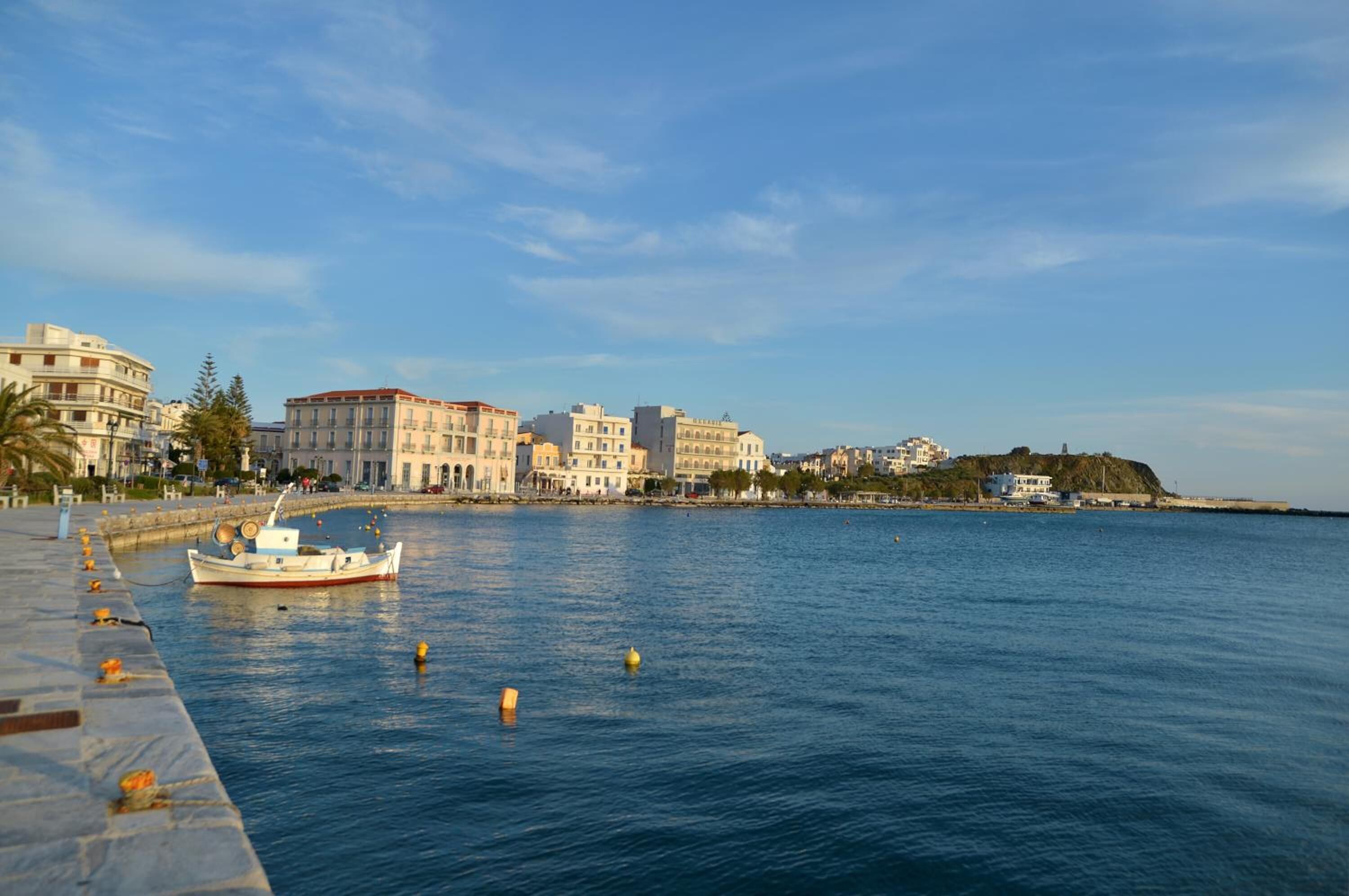 A waterfront view with buildings, a dock, and a calm sea.