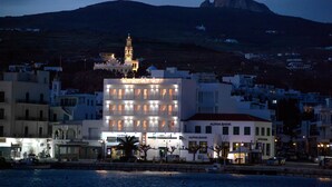 A coastal town with a prominent building featuring balconies and a bank named "Alpha Bank". - Nama Boutique Hotel (Tinos)
