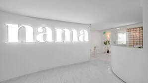A modern reception area with a large illuminated sign reading "nama" and a clean, minimalist design. - Nama Boutique Hotel (Tinos)