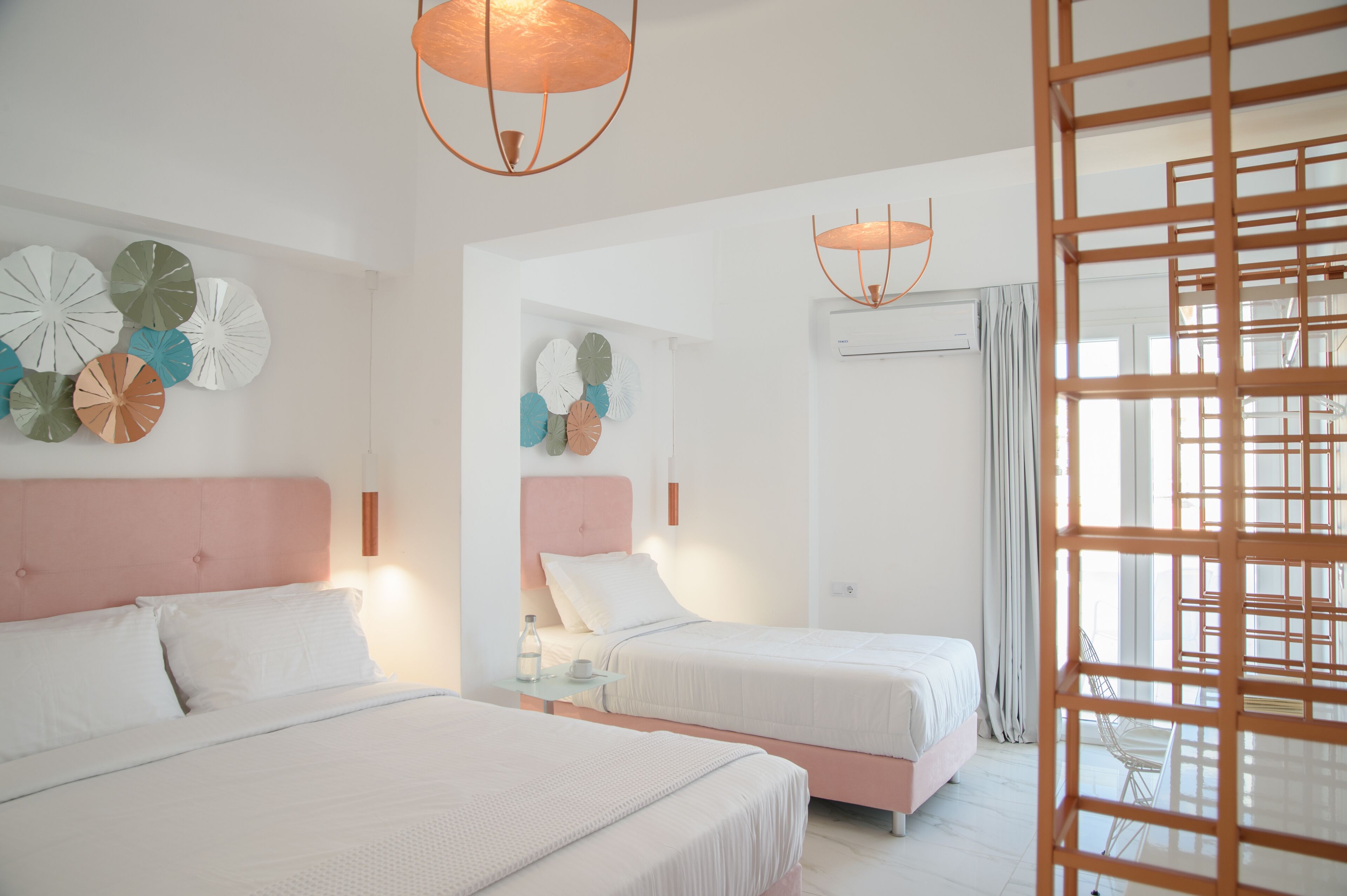 Une chambre d’hôtel avec deux lits, une grande fenêtre et des œuvres d’art décoratives au mur.