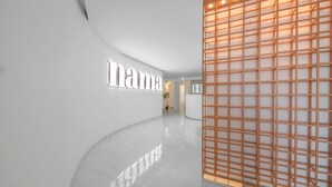 A modern interior with a curved white wall, a 'nama' sign, and a wooden grid structure. - Nama Boutique Hotel (Tinos)