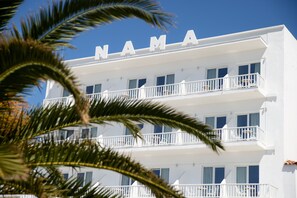 A multi-story hotel with balconies and a clear blue sky. - Nama Boutique Hotel (Tinos)