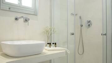 A bathroom with a white sink, a mirror, a shower, and a towel rack.