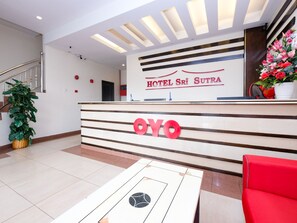 Un mostrador de recepción de hotel con diseño moderno, con un cartel que dice "HOTEL Sri Sutra" y el logotipo "OYO".
