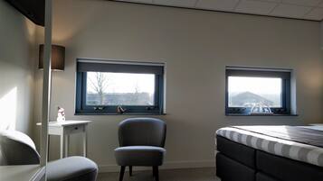 A bedroom with two windows, a chair, a bed, and a desk.