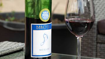 Een fles Barefoot Merlot en een wijnglas op een glazen tafel.