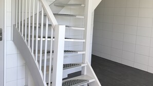 Een witte trap met een leuning en een plateau.