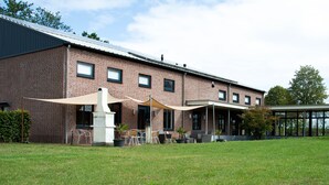 Een bakstenen gebouw met een patio, zonnescherm en buitenmeubilair.