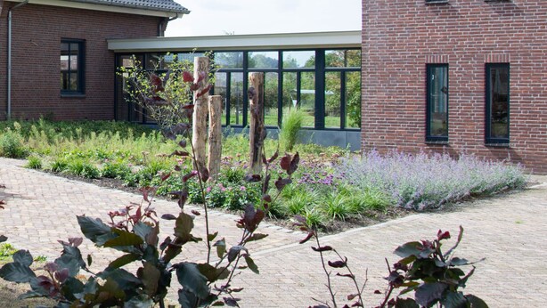 Een gebouw van baksteen met grote ramen en een verharde looppad.