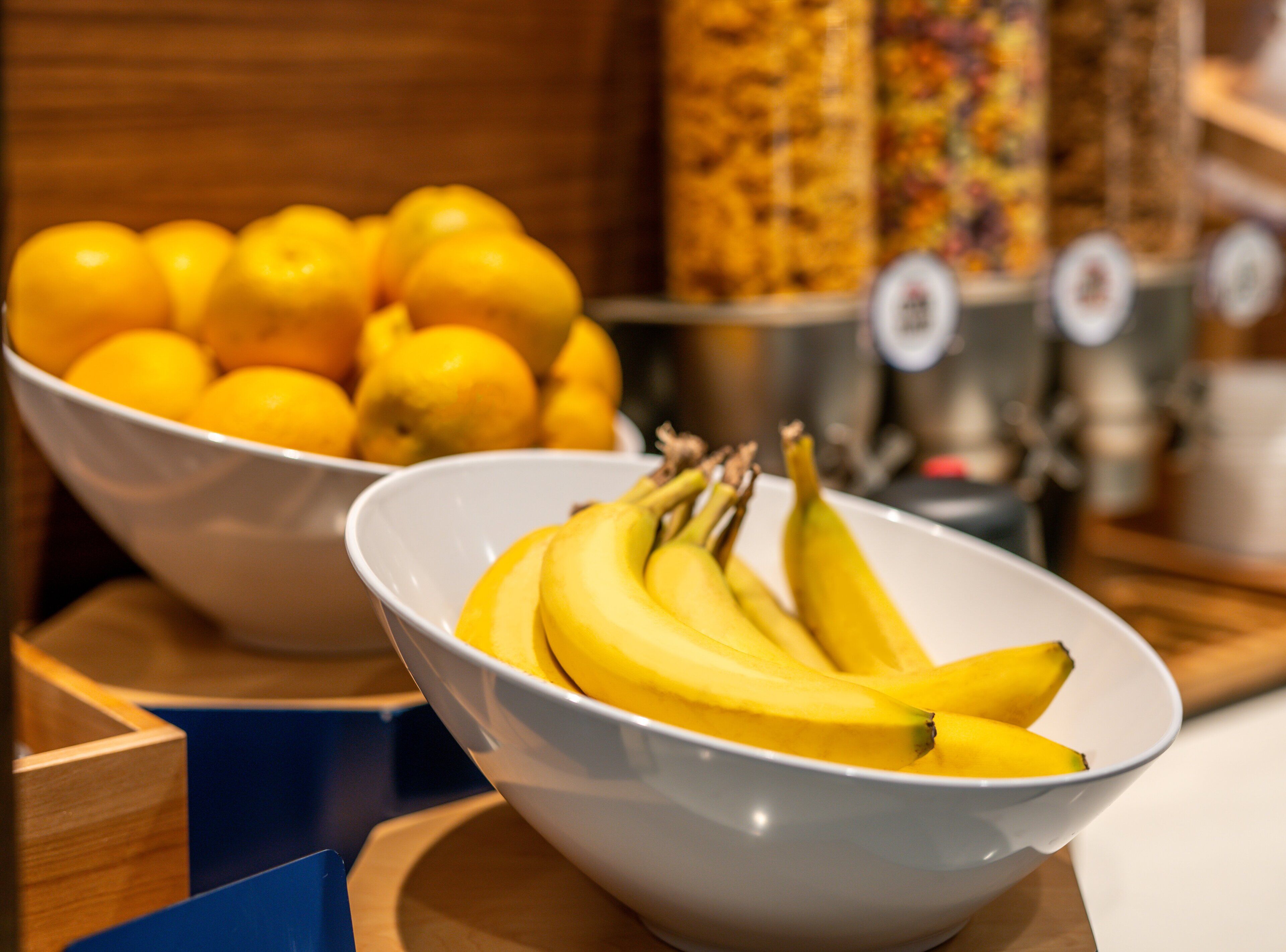 A bowl of bananas and lemons on a wooden table.