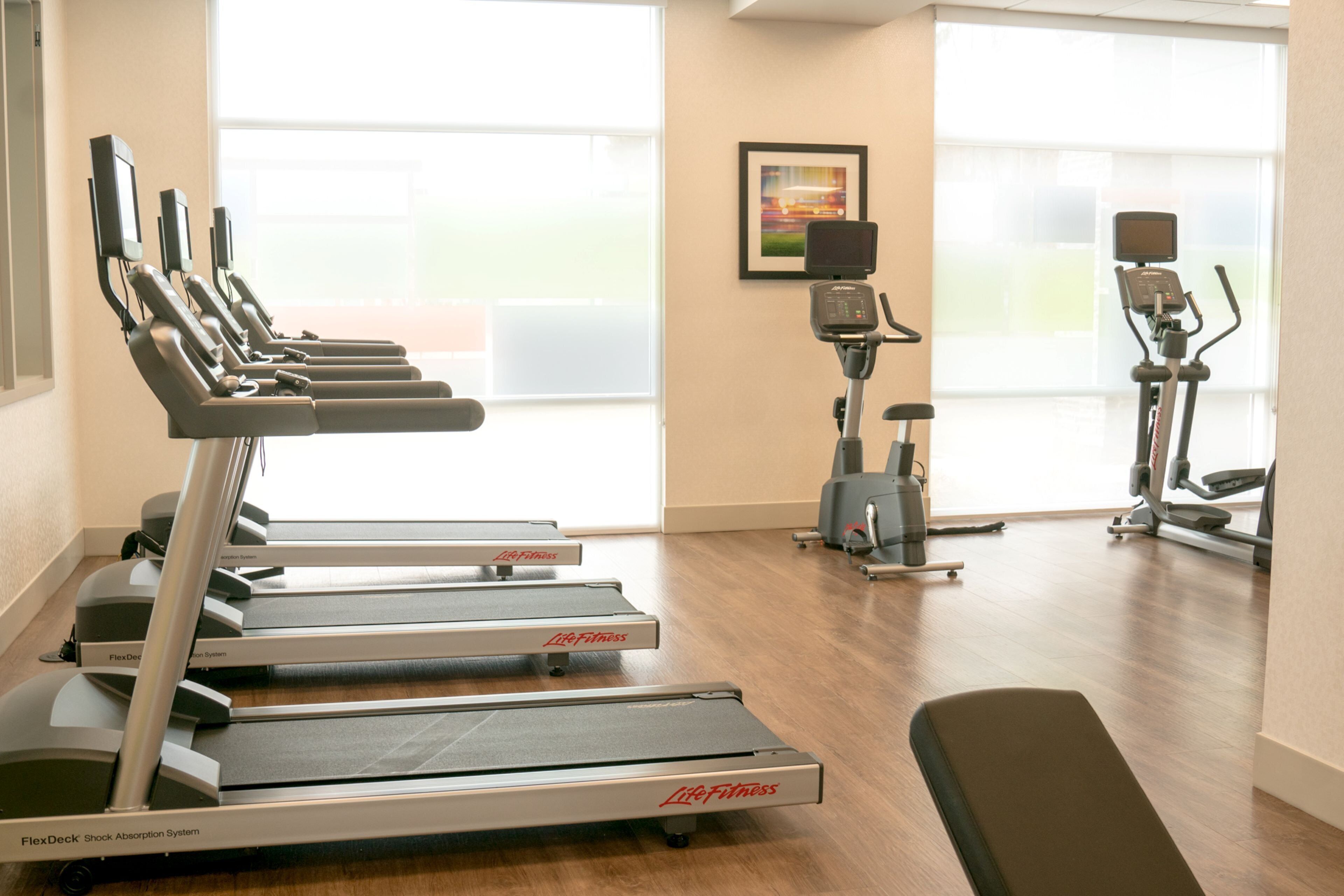 Une salle de sport équipée de tapis de course, d’un vélo d’appartement et d’un rameur.