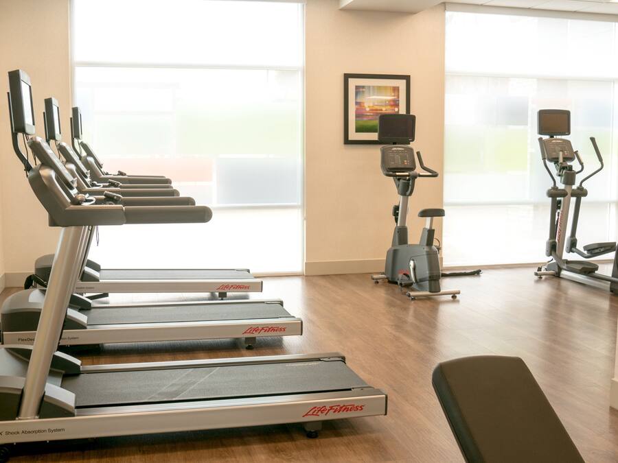 Une salle de sport équipée de tapis de course, d’un vélo d’appartement et d’un rameur.