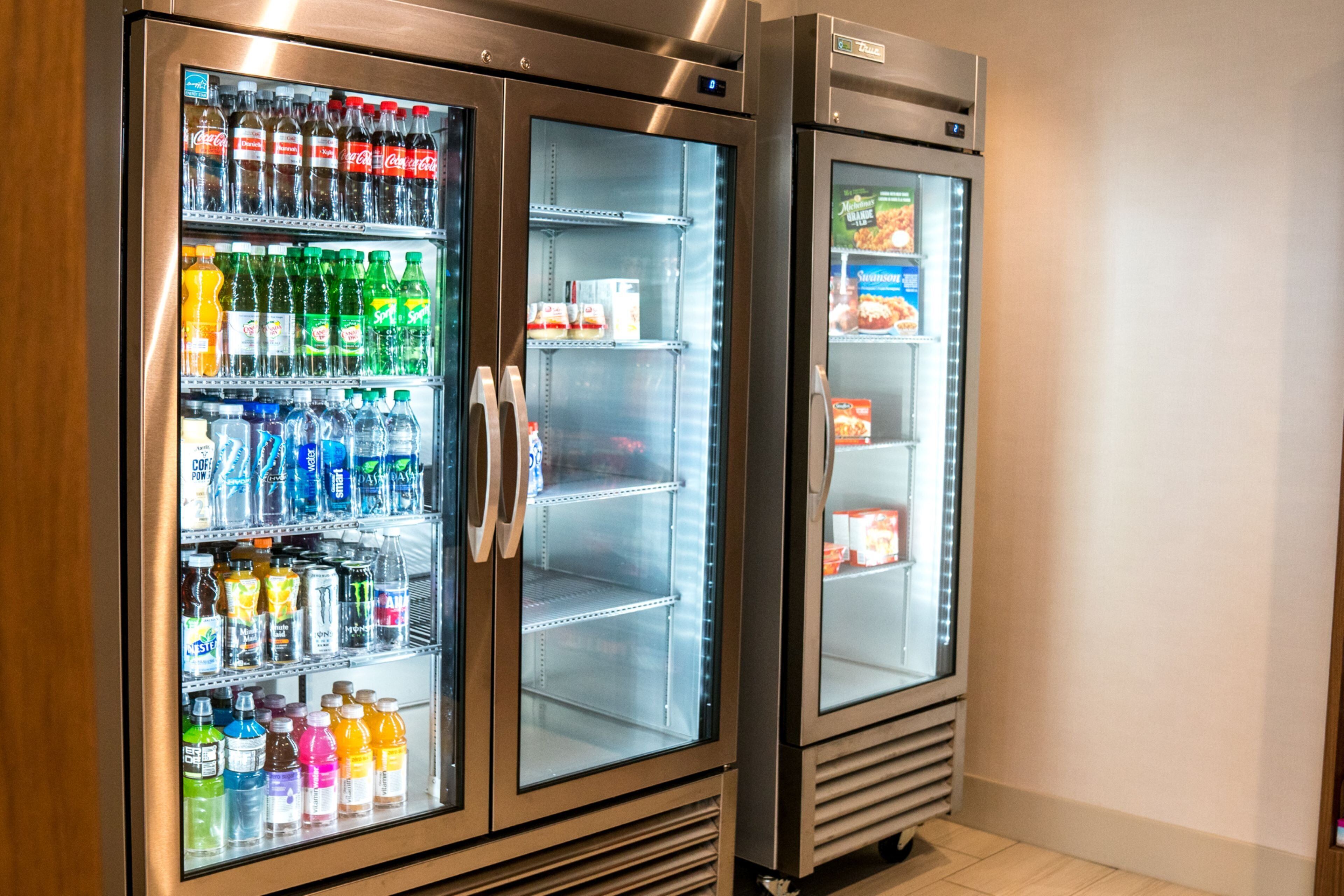 Dos dispensadores de bebidas de acero inoxidable con puertas de cristal, llenos de diversas opciones.