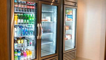 Dos dispensadores de bebidas de acero inoxidable con puertas de cristal, llenos de diversas opciones.