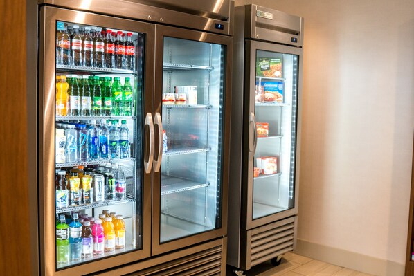 Two stainless steel beverage dispensers with glass doors, stocked with various drinks.
