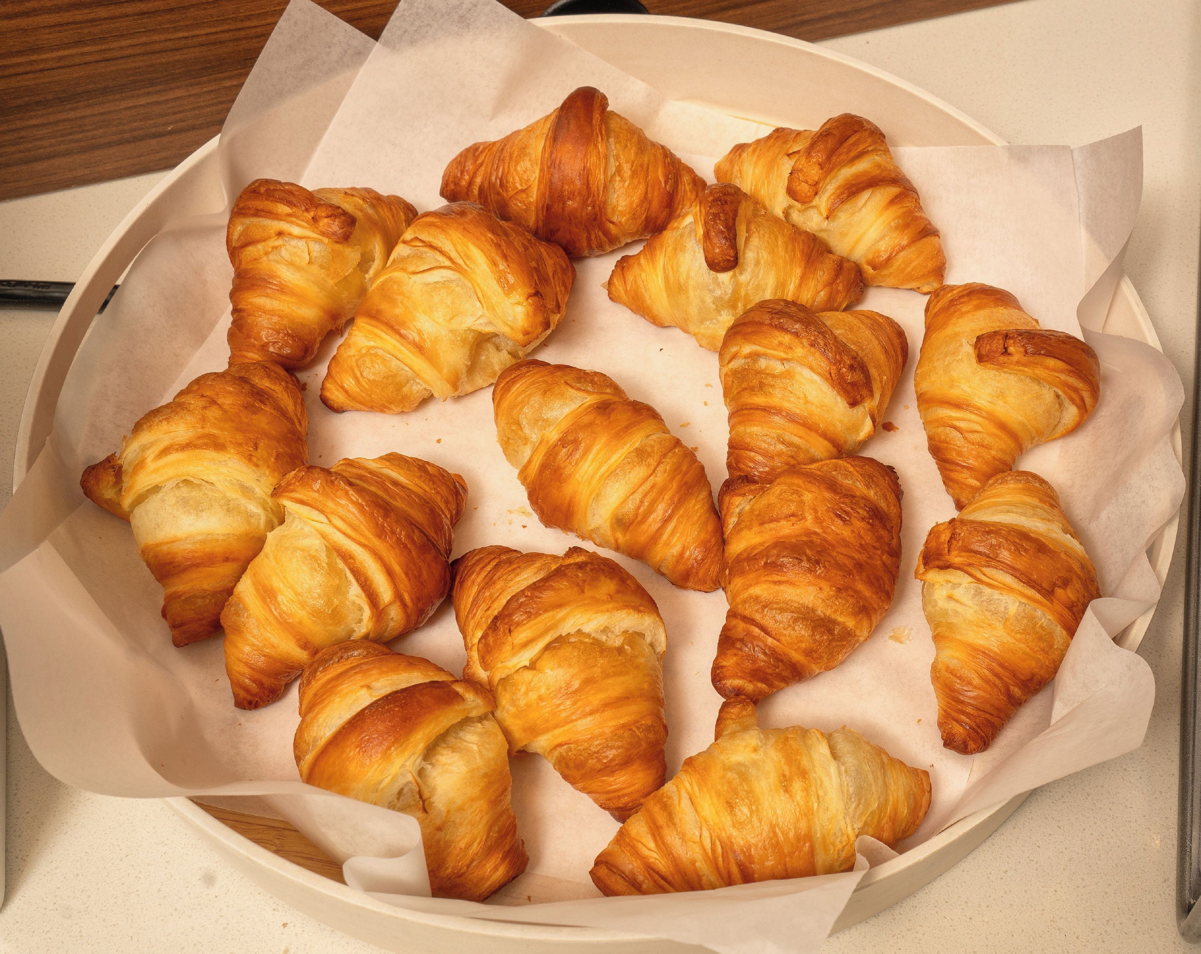 A box containing several golden-brown croissants.