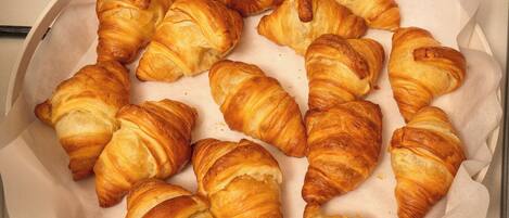 A box containing several golden-brown croissants.