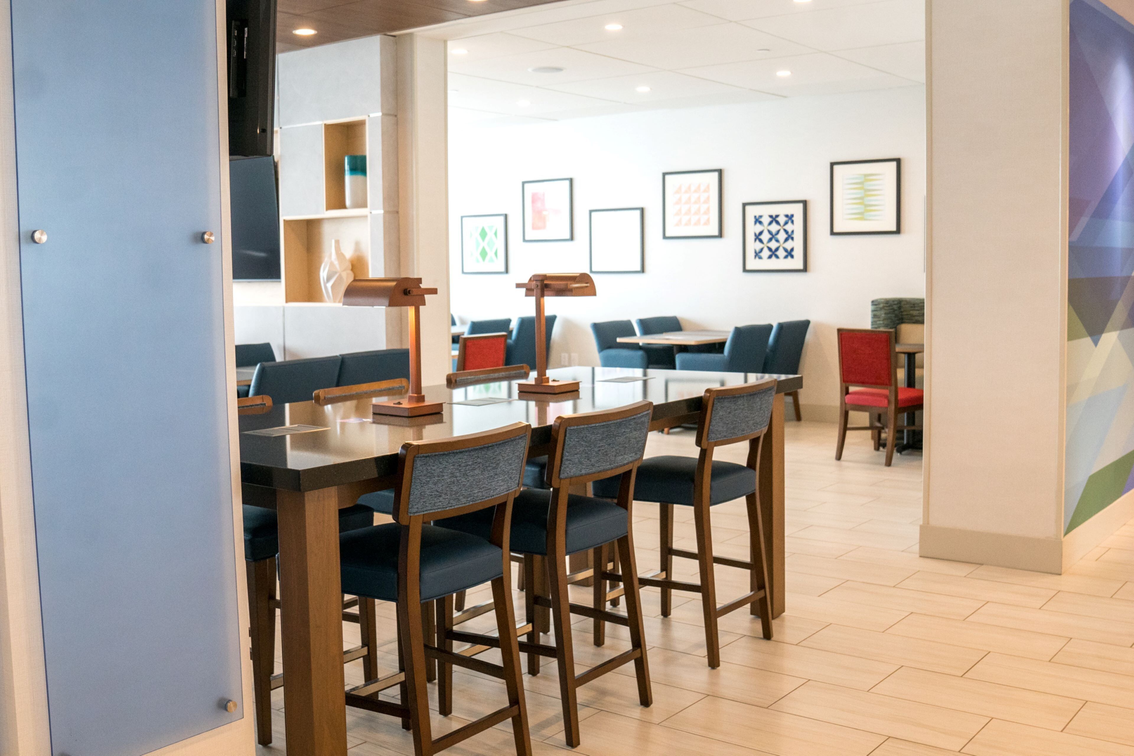 A modern dining area with a long table and chairs, a coffee station, and a seating area with sofas and chairs.