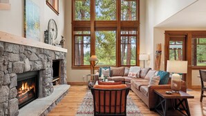 A cozy living room with a stone fireplace, large windows, and a comfortable seating area.