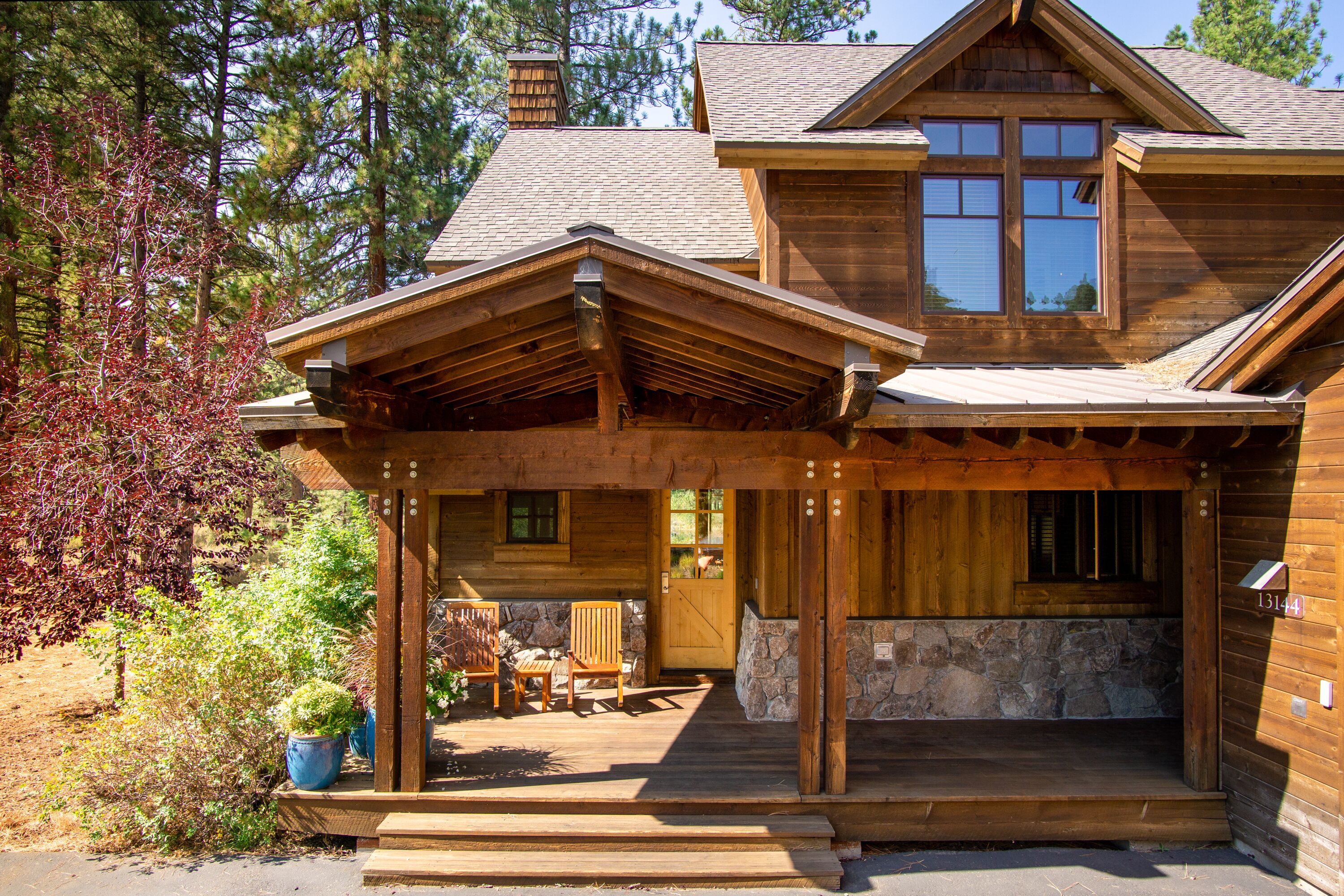 A wooden cabin with a porch, stone foundation, and a number plaque.