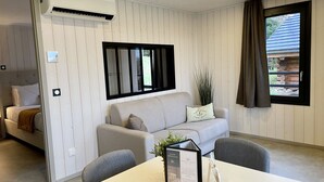 A modern room with a sofa, a dining table, and a window with curtains. - Domaine les 2 Mondes (Aydat)