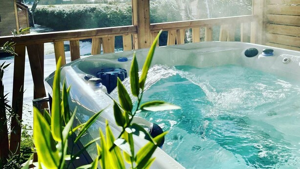 A hot tub with a wooden deck and a view of a snowy landscape. - Domaine les 2 Mondes (Aydat)