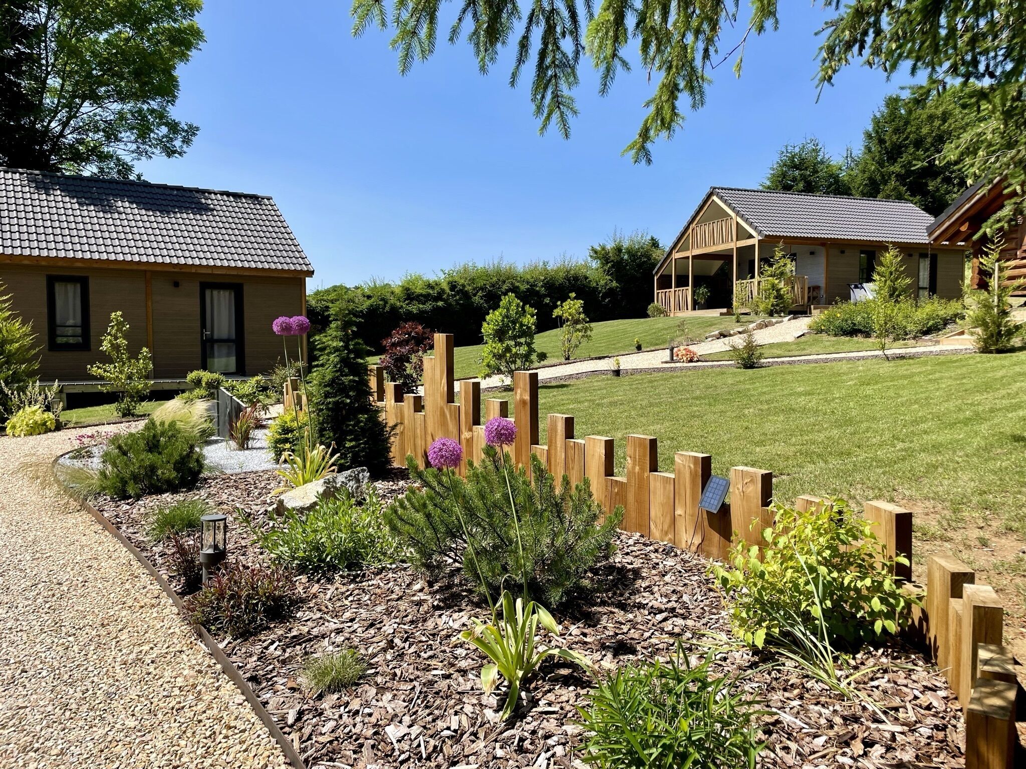 A residential area with a house, a wooden fence, and a garden with various plants and flowers.