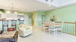 A spacious living area with a dining table and chairs, a sofa, and a kitchen in the background. - Dog Friendly Home with Ocean View from Balcony by RedAwning (Fernandina Beach)
