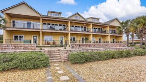 A multi-story hotel with balconies, a stone retaining wall, and a gravel pathway. - Dog Friendly Home with Ocean View from Balcony by RedAwning (Fernandina Beach)