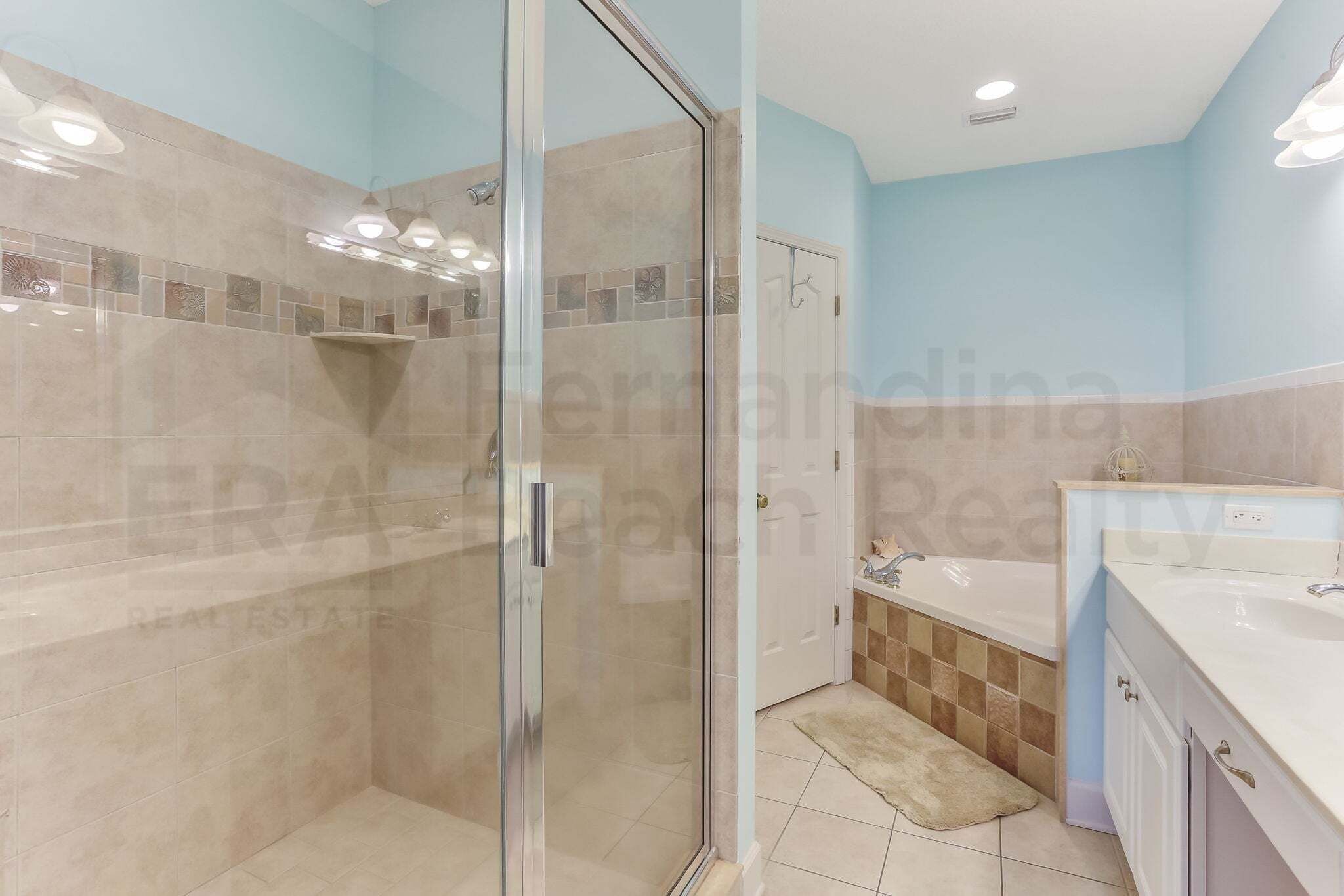 A bathroom with a glass shower enclosure, a bathtub, and a sink.