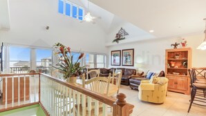 A spacious living area with a high ceiling, a staircase, and a view of the outside. - Dog Friendly Home with Ocean View from Balcony by RedAwning (Fernandina Beach)
