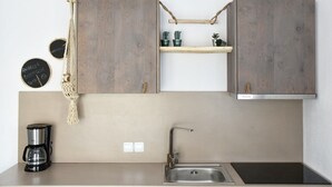 Een keuken met houten kastjes, een macramé opberger, een koffiezetapparaat en een spoelbak.