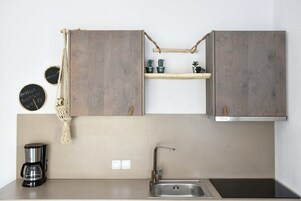 Una cocina con gabinetes de madera, un organizador colgante de macramé, una cafetera y un lavamanos.