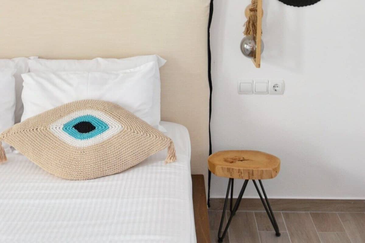 A bedroom with a bed, a bedside table, a wall-mounted lamp, and three circular wall hangings.