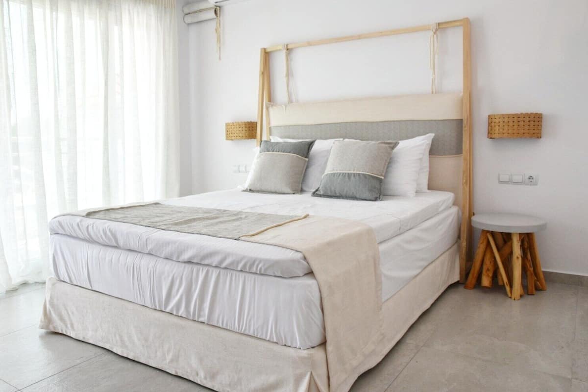 A modern bedroom with a bed, bedside tables, and a view of the outside.