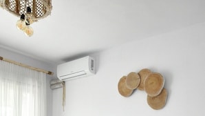 Een moderne slaapkamer met een groot bed, een grijs hoofdeinde en een nachtkastje met een boek.