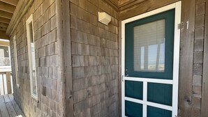 A wooden exterior with a green door, a white window, and a porch.