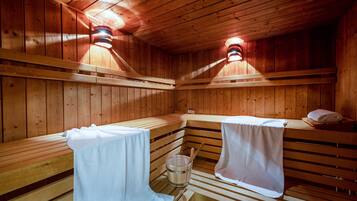 Una sauna con bancos de madera, un cubo y toallas.