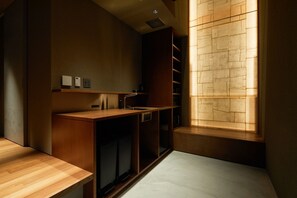 A compact, modern room with built-in wooden furniture, a built-in shelf, and a window with a brick pattern.