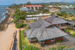 Zona residencial costera con casas de tejados pronunciados y una playa al fondo.